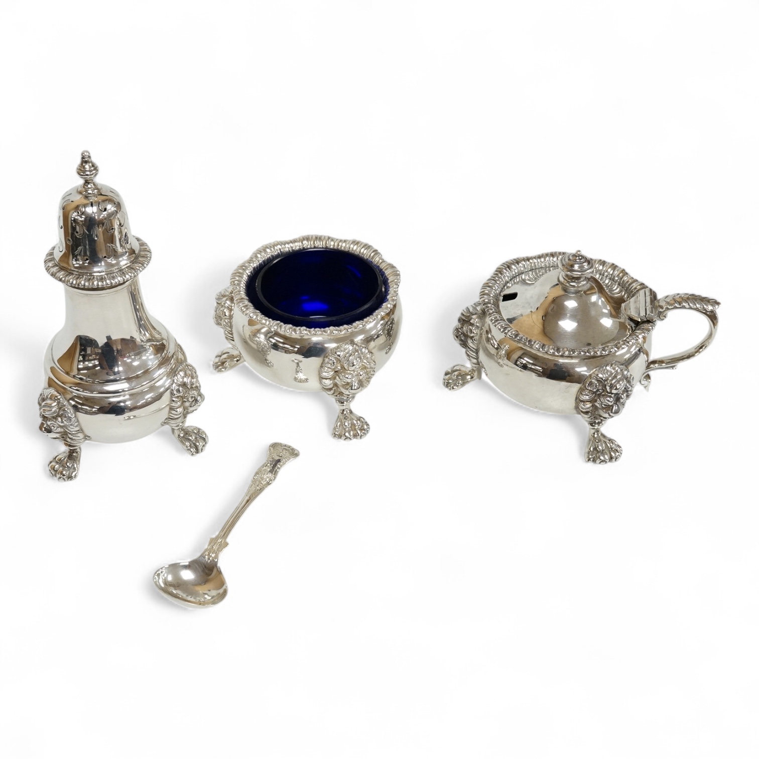 A George VI silver three piece condiment set by Mappin & Webb, London, 1937, with blue glass liners, one associated, pepper, 13.9cm, 26.5oz.